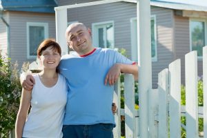 happy couple posing in front of his home