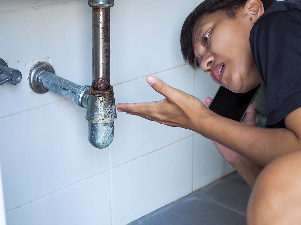 A homeowner looking puzzled while inspecting a portion of plumbing Temecula, CA